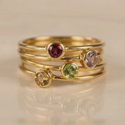 A video showcasing a Personalized tiny birthstone round gemstone rings with garnet purple amethyst peridot citrine birthstones vermeil gold plating. Wear them alone of stack them on the same finger