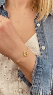 Model is wearing a gold plated open circle pendant charm birthstone bracelets featuring clear quartz birthstones. april birthstones. 