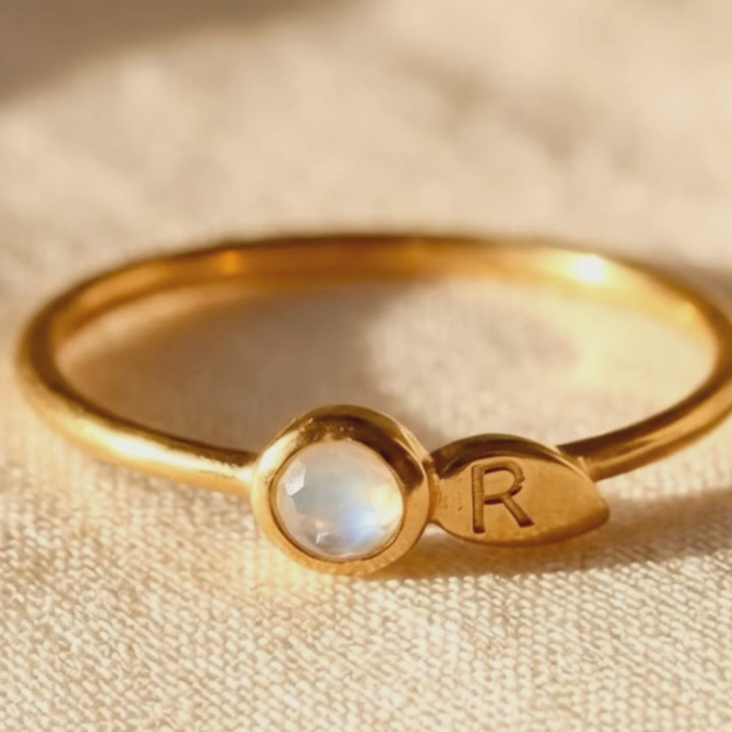 A video showcasing 18K vermeil gold birthstone initial rings with faceted gemstones and leaf charms. Comes in rose or yellow gold, or sterling silver