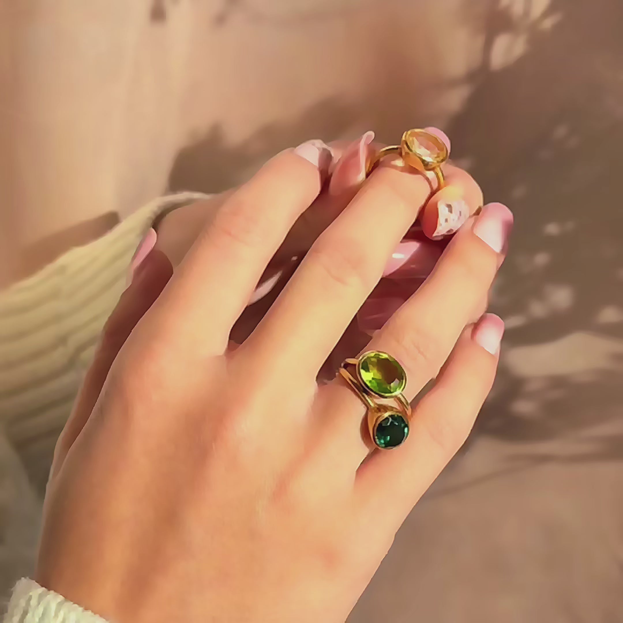 Video of stackable oval birthstone rings sparkling in warm light—two bezel-set gemstones on slim gold bands styled as stacking rings. Minimalist, dainty oval gemstone rings perfect for everyday wear or layering; available in sterling silver, gold filled, or rose gold filled, hypoallergenic and nickel-free. Create a family birthstone ring or mom ring with multiple stones; great personalized gift for her for birthday, anniversary, Christmas,Mother’s Day, bridesmaid, or graduation; handmade by Danique Jewelry.