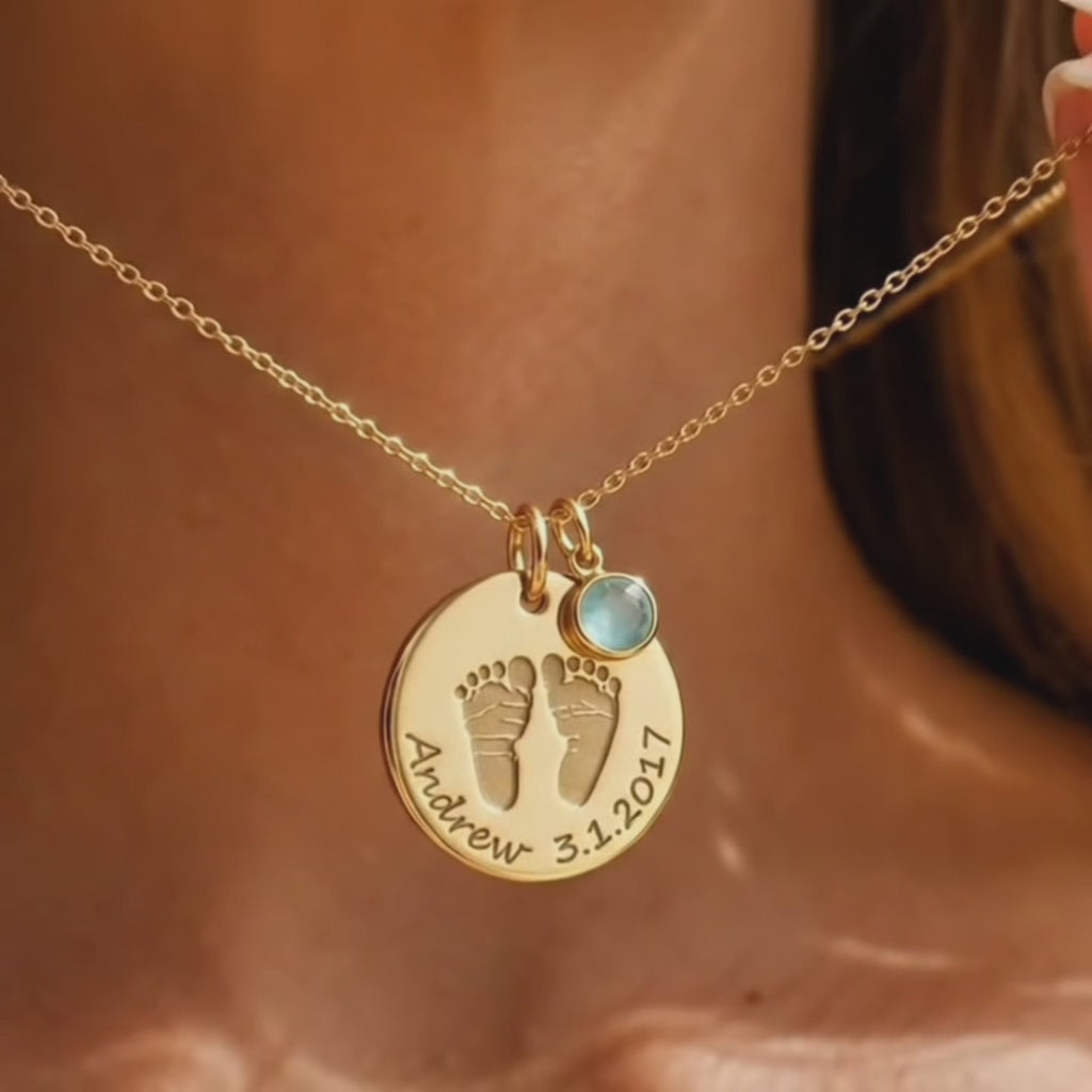 video showcasing custom baby footprint necklace with round gold disc pendant engraved with tiny newborn feet and handwritten style name and birth date, paired with a dainty peridot style birthstone charm on a delicate gold chain, sentimental keepsake jewelry for new moms and dads, perfect push present, baby shower or first Mother’s Day gift, personalized footprint necklace handmade in sterling silver or gold vermeil