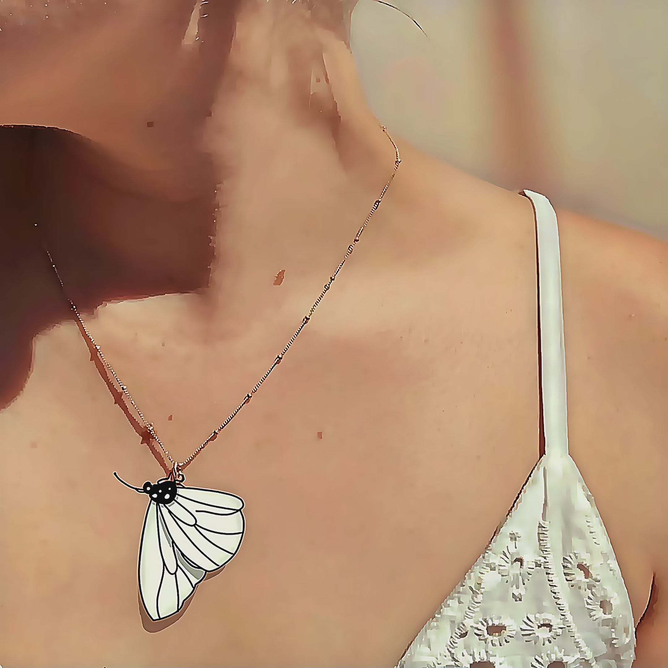 Video showcasing a delicate butterfly-inspired gold necklace being held at the collarbone, featuring an open wing outline set with tiny custom birthstones; personalized butterfly birthstone necklace, meaningful gift for moms, daughters or nature lovers, and elegant everyday jewelry piece.