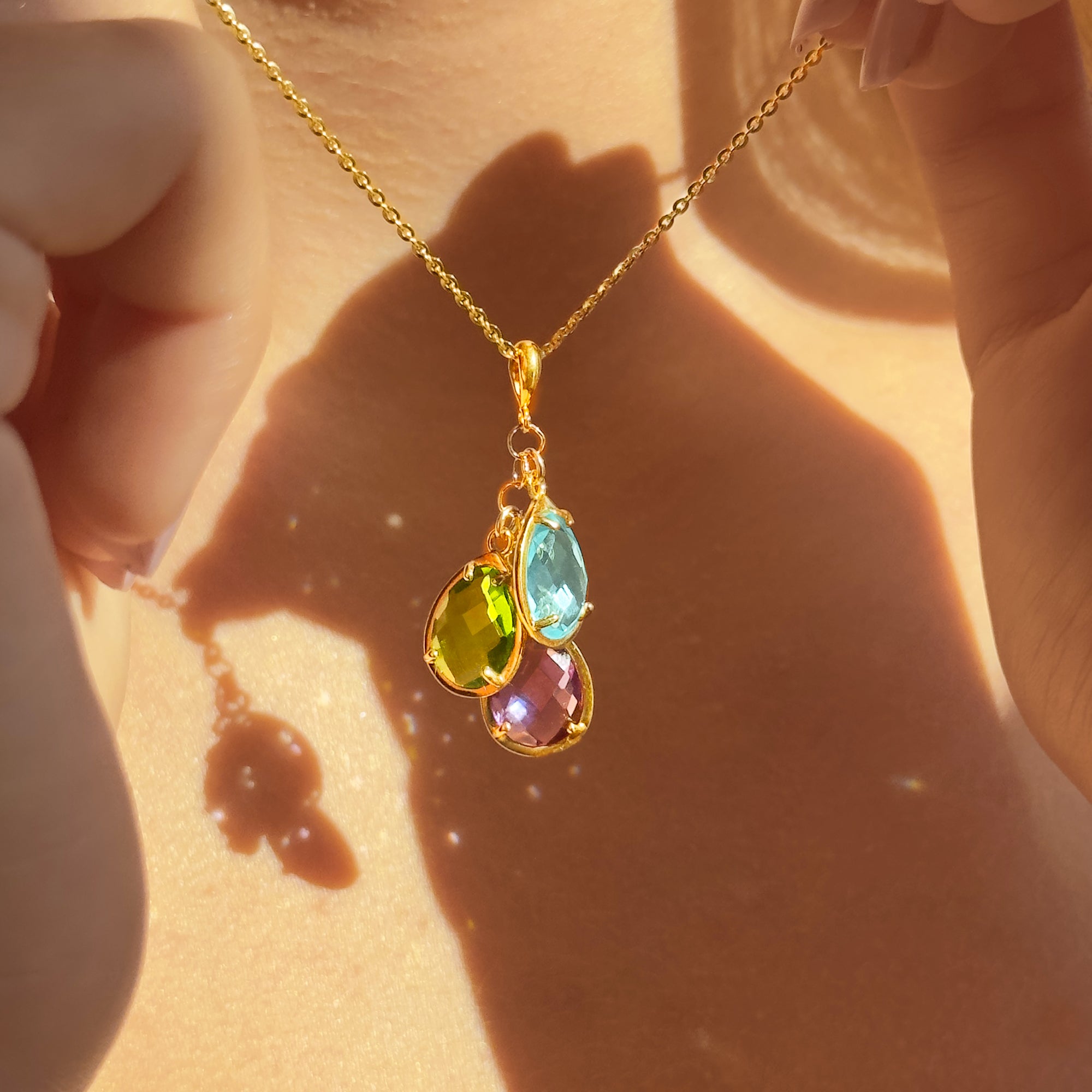Custom birthstone mom necklace with sparkling teardrop pendants resting against the collarbone, shown in warm sunlight to highlight the gold filled setting and colorful family birthstones. Dainty layered style perfect for everyday wear, Mother’s Day, birthday, or Christmas gift for mom, new mom, or grandma, personalized with children’s birthstones for a sentimental keepsake.