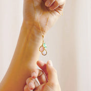 Close-up of hand gently holding a custom teardrop birthstone mom necklace, highlighting the size, movement, and fine detailing of the prong-set stones and delicate chain. Personalized family birthstone pendant that can be customized with multiple birthstones, a unique Mother’s Day, birthday, or Christmas gift idea for mom or grandmother who cherishes her children and grandchildren.