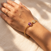 Close-up of personalized purple amethyst birthstone bracelet with initial charm worn on the wrist.
