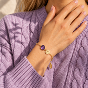 Woman wearing a personalized purple amethyst birthstone bracelet with custom initial charm on a delicate gold chain.
