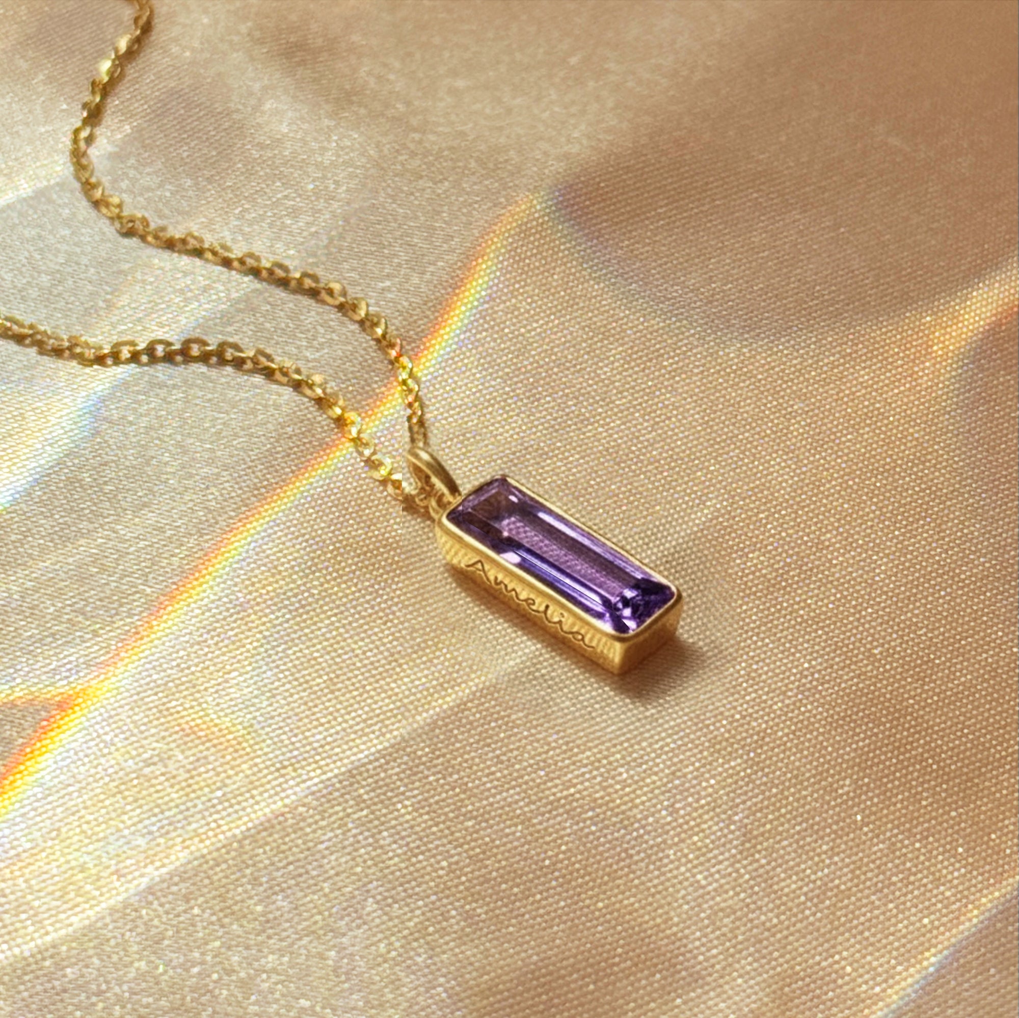vertical bar name necklace featuring a baguette amethyst bar pendant resting at the collarbone, personalized with subtle side engraving, shown in bright sunlight on gold filled chain for a warm glow, stylish February birthstone bar necklace she can wear every day or dress up for evenings, trending baguette birthstone necklace style that looks beautiful layered with other delicate chains and makes a chic personalized gift for her