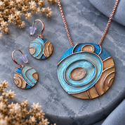 Tidal Orbit turquoise sculptural pendant necklace and matching earrings displayed on gray stone

