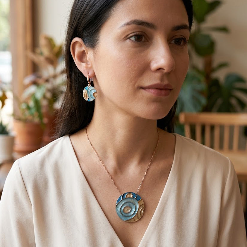 Woman wearing Tidal Orbit turquoise statement pendant necklace and matching circular earrings

