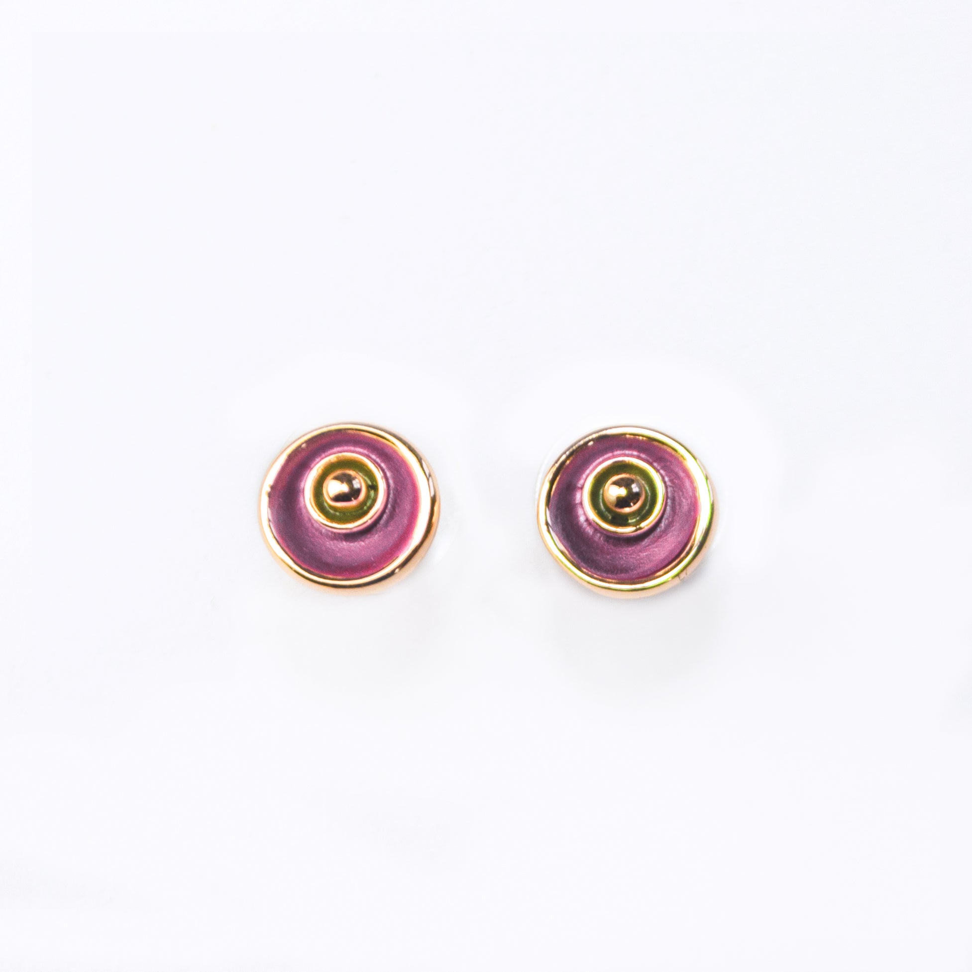 A pair of circular abstract flower earrings against a white background with rose gold plating and painted in pink and gray