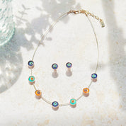 Adjustable Choker Necklace against a textured stone background with a brown steel cable chain and seven rose gold plated circular flower charms painted in blue, teal, and orange with a pair of matching circular flower earrings in blue and teal