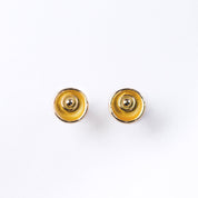 A pair of circular abstract flower earrings against a white background with rose gold plating and painted in gold and beige