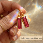 Close-up of Ruby Quartz baguette earrings held between fingers for scale