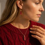 Woman wearing Ruby Quartz bar earrings with a matching necklace and red sweater