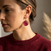 Model wearing medium round ruby quartz earrings with a burgundy sweater for July birthstone styling.