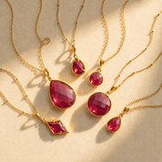 Ruby quartz July birthstone necklace collection with multiple pendant shapes shown in warm sunlight.