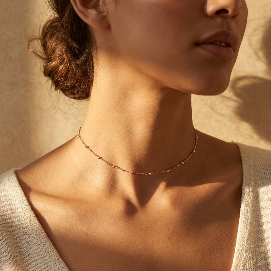 Dew Drops choker necklace featuring a delicate satellite chain with evenly spaced bead accents, photographed on a model wearing a minimalist choker style necklace in warm natural light, showcasing a dainty everyday necklace handmade in the USA and designed for layering with other gold or silver necklaces