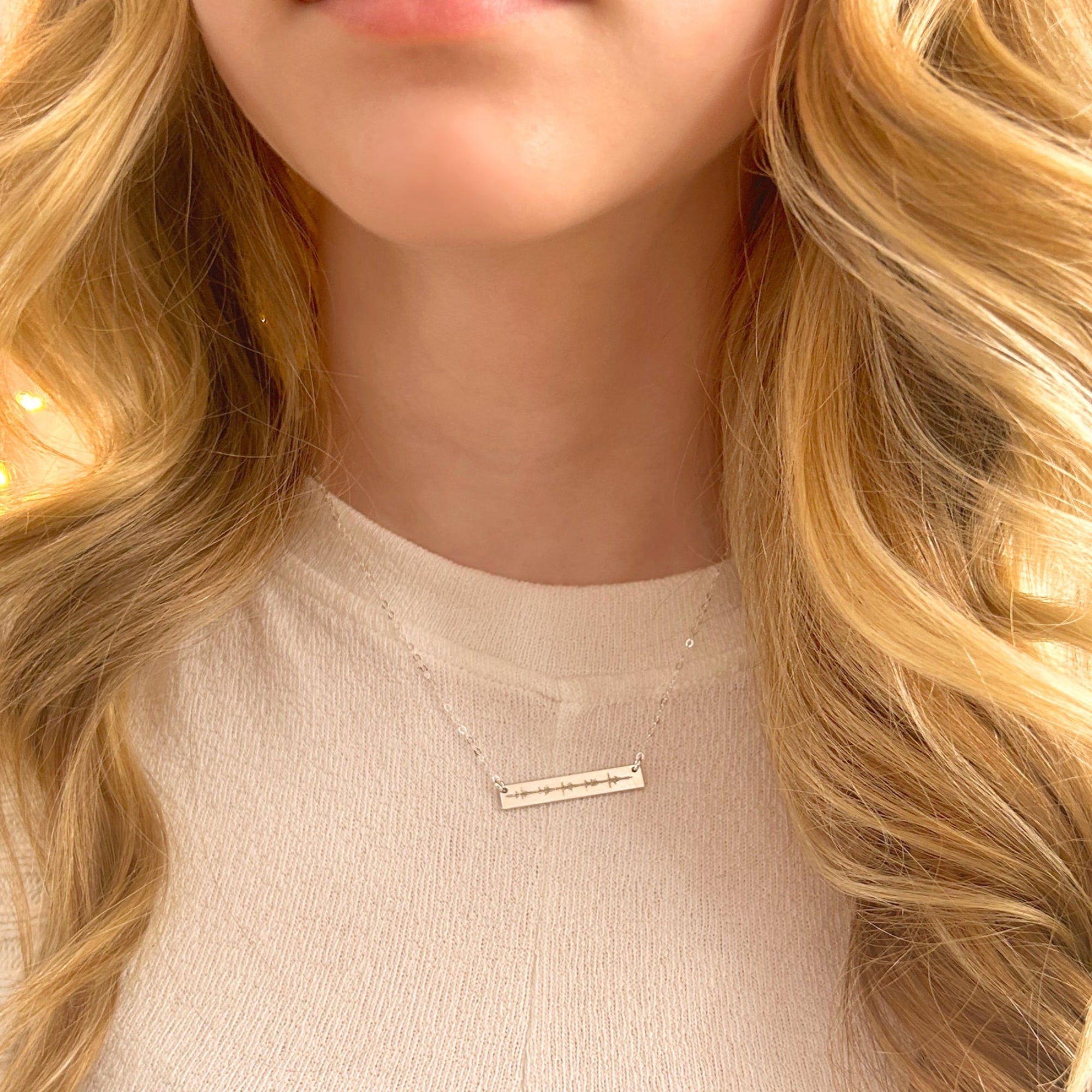 A person with blonde hair wears a silver engraved heartbeat necklace. Personalized bar necklace, minimalist jewelry, layering necklace, ekg jewelry, sonogram jewelry, custom engraved heartbeat necklace, sterling silver necklace, front and back engraved sterling silver necklace for women, gold filled necklace for women, rose gold filled necklace for women