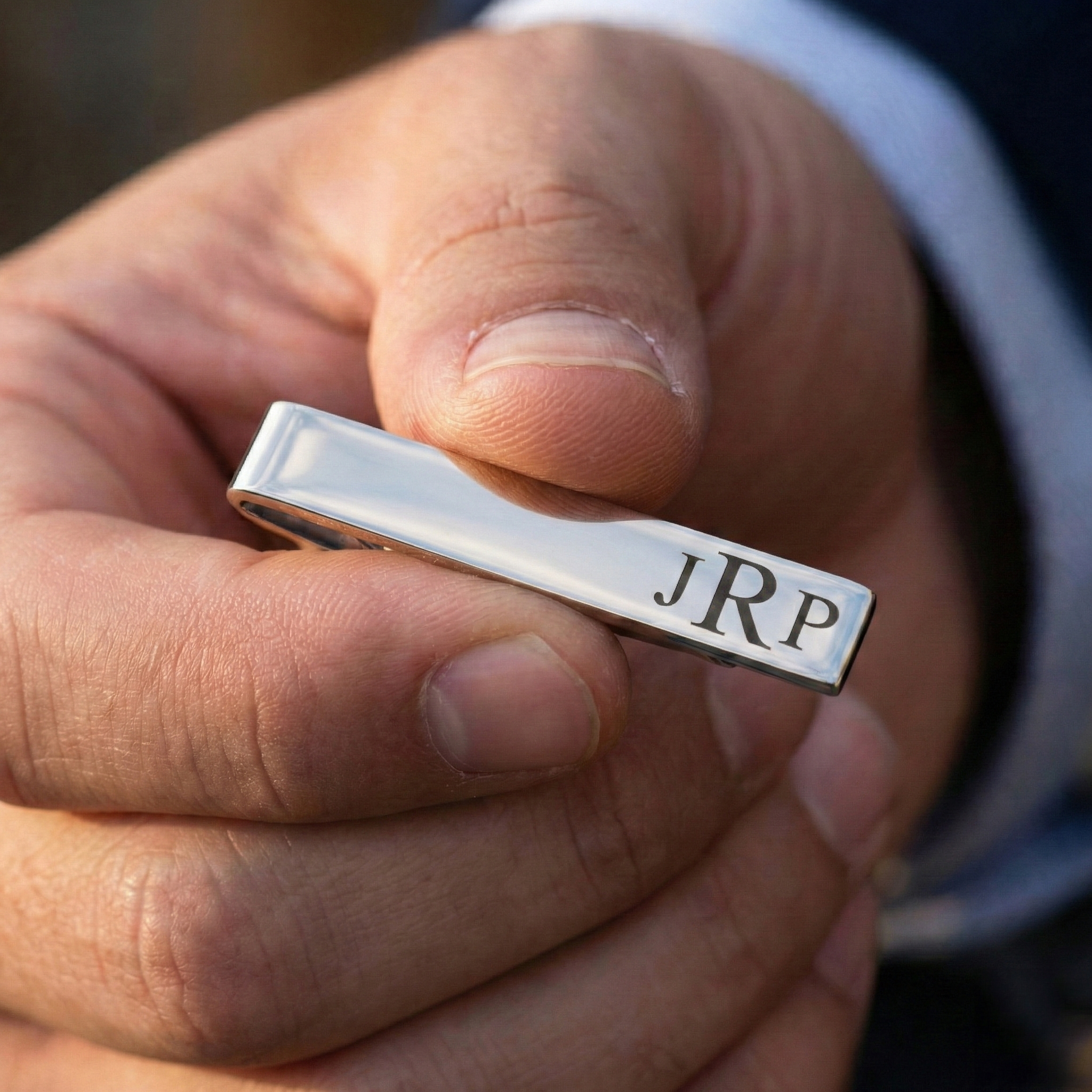 silver-tie-clip-in-hand.png