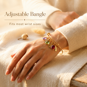 Adjustable gold birthstone bangle worn on a woman’s wrist with personalized name and gemstone charms.