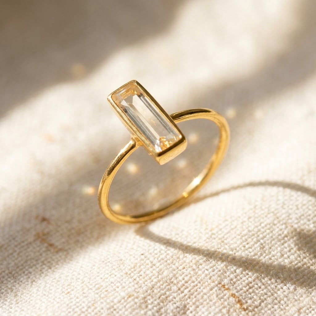 Single clear quartz bar ring on white background, dainty gold rectangle gemstone ring