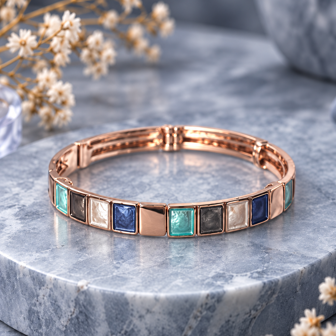 Rose gold Mosaic Squares bangle bracelet with teal blue and gray color block design on gray stone

