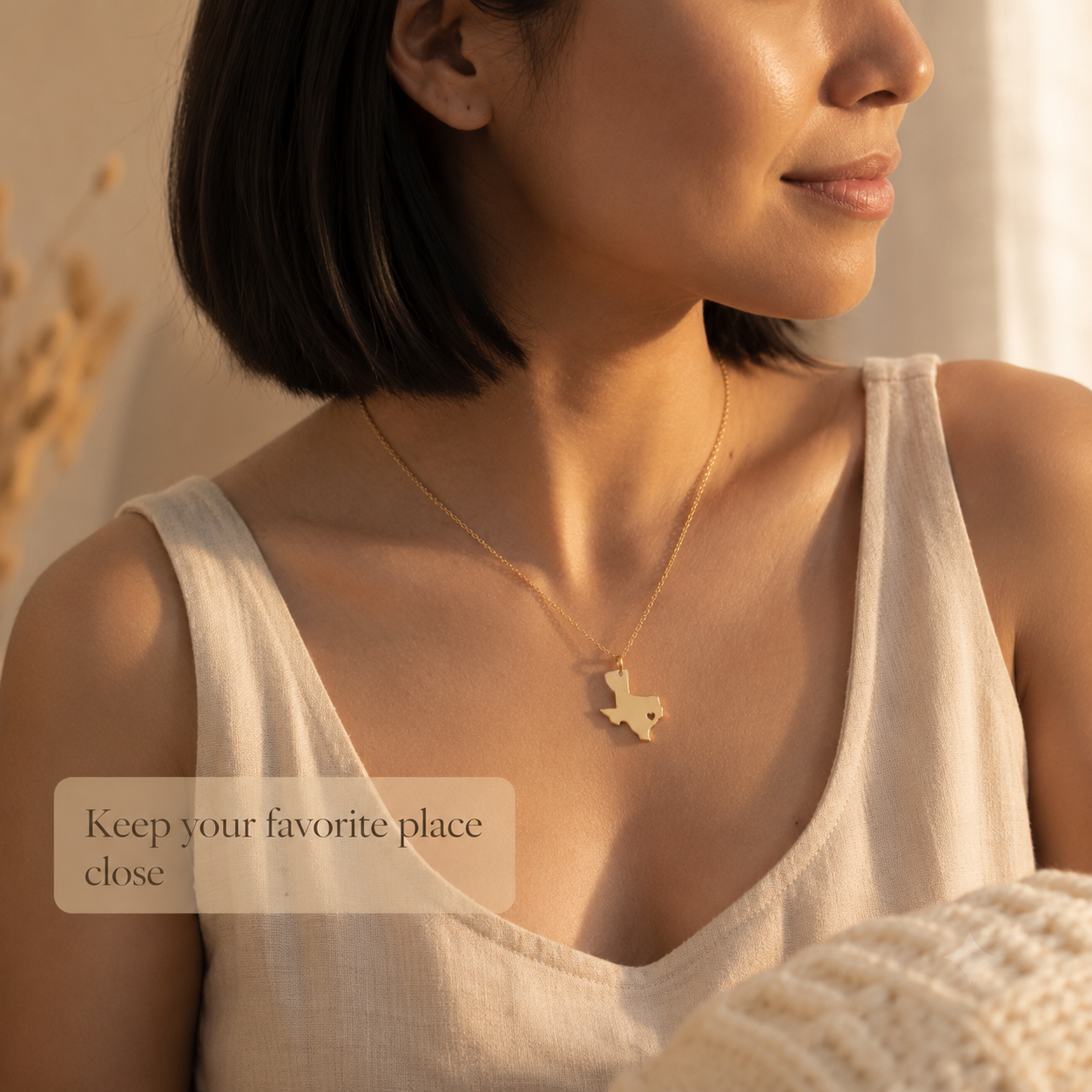Woman wearing a personalized gold state map necklace with heart cutout
