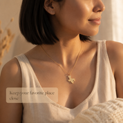 Woman wearing a personalized gold state map necklace with heart cutout
