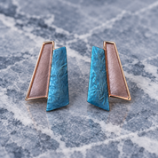 Ocean Breeze geometric Fan stud earrings with teal blue and metallic layered panels on gray stone
