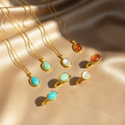 Elegant collection of matching oval gemstone necklaces and rings displayed on shimmering champagne satin, featuring bezel-set stones in moonstone, turquoise, green chalcedony and goldstone with rich gold settings. Coordinated gemstone jewelry set ideal for gifting or mix-and-match styling, perfect for birthdays, anniversaries, Mother’s Day or Christmas, offering minimalist everyday wear pieces for her, mom, sister or best friend.