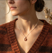 Model wearing a sunstone necklace with a rust sweater, showing a delicate orange gemstone pendant in a gold setting for everyday styling.
