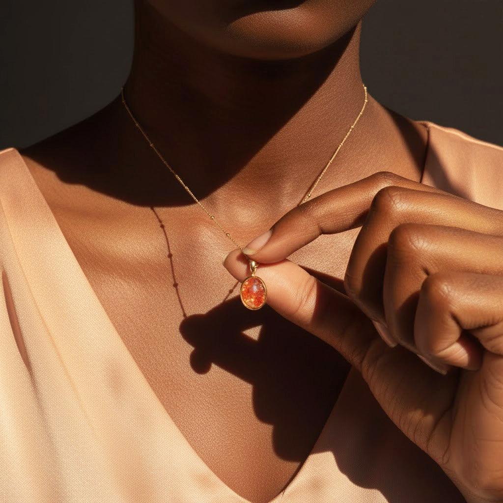 Model wearing a white lace blouse holds Dainty Large Oval Sunstone Bezel Set Pendant on a gold filled satellite chain. Sunstone Jewelry Necklace, Natural Orange Sunstone, Celestial Sun Jewelry, Summer Birthday
