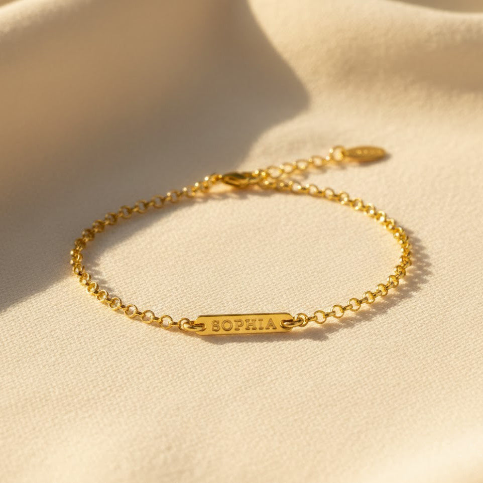 tiny bar bracelet in 18k gold vermeil displayed on soft neutral fabric, featuring a slim rectangular bar engraved with the name Sophia in a delicate uppercase font, attached to a dainty chain with small bead accents, customizable with initials, names or dates, available in multiple font options and adjustable or fixed lengths, minimalist personalized bracelet perfect for everyday wear, bridesmaid gifts, birthdays or meaningful monogram jewelry for women