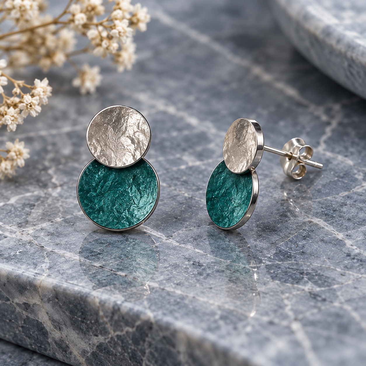Turquoise and Silver hammered double disc stud earrings displayed on gray stone

