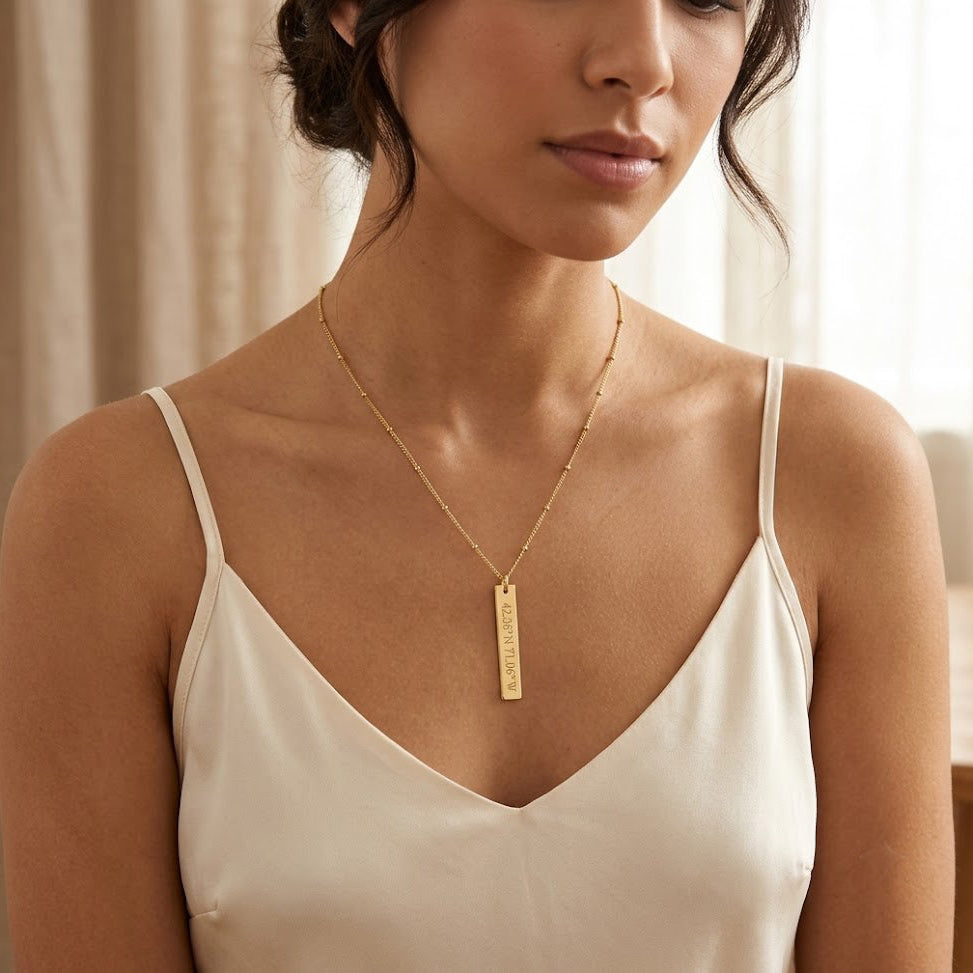 Woman wearing a custom gold vertical bar necklace with a white camisole