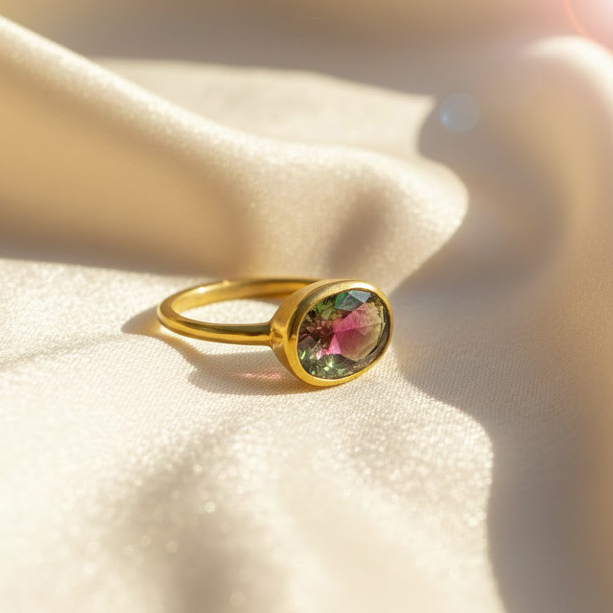 watermelon tourmaline oval bezel ring in 18k yellow gold vermeil resting on soft champagne satin fabric, multicolor pink-green tourmaline gemstone reflecting autumn tones, minimalist birthstone ring designed for October birthdays or anniversaries, ideal as a personalized gift for her such as mom, sister or best friend, stackable gemstone ring finished in sterling silver option, everyday dainty ring celebrating color and meaning.