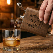 Personalized wooden flask pouring whiskey into glass, featuring engraved monogram design. Custom engraved flask made for bourbon and whiskey lovers.