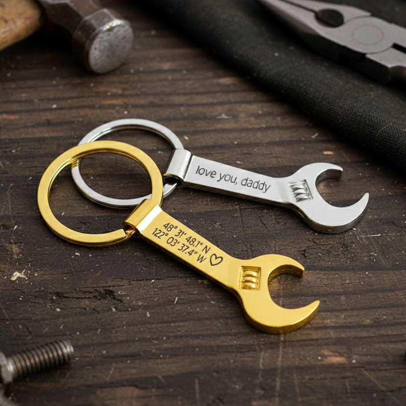 Single gold toned wrench keychain with special GPS coordinates engraved and a heart emoji. Single silver toned wrench bottle opener keychain with special message engraved.