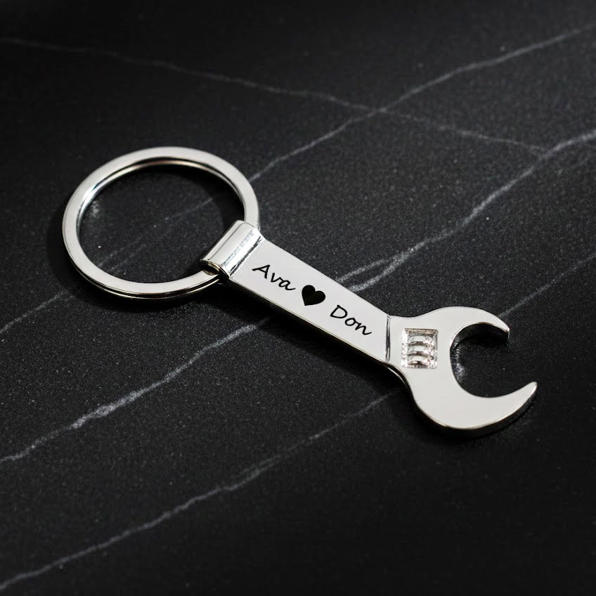 Single silver tone wrench keychain engraved with two names in script font. bottle opener keychain