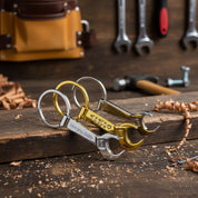 Three keychains, first silver tone wrench keychain engraved with special message. middle keychain Single gold toned wrench keychain with special GPS coordinates engraved and a heart emoji. last silver toned keychain with two names engraved. bottle opener keychain