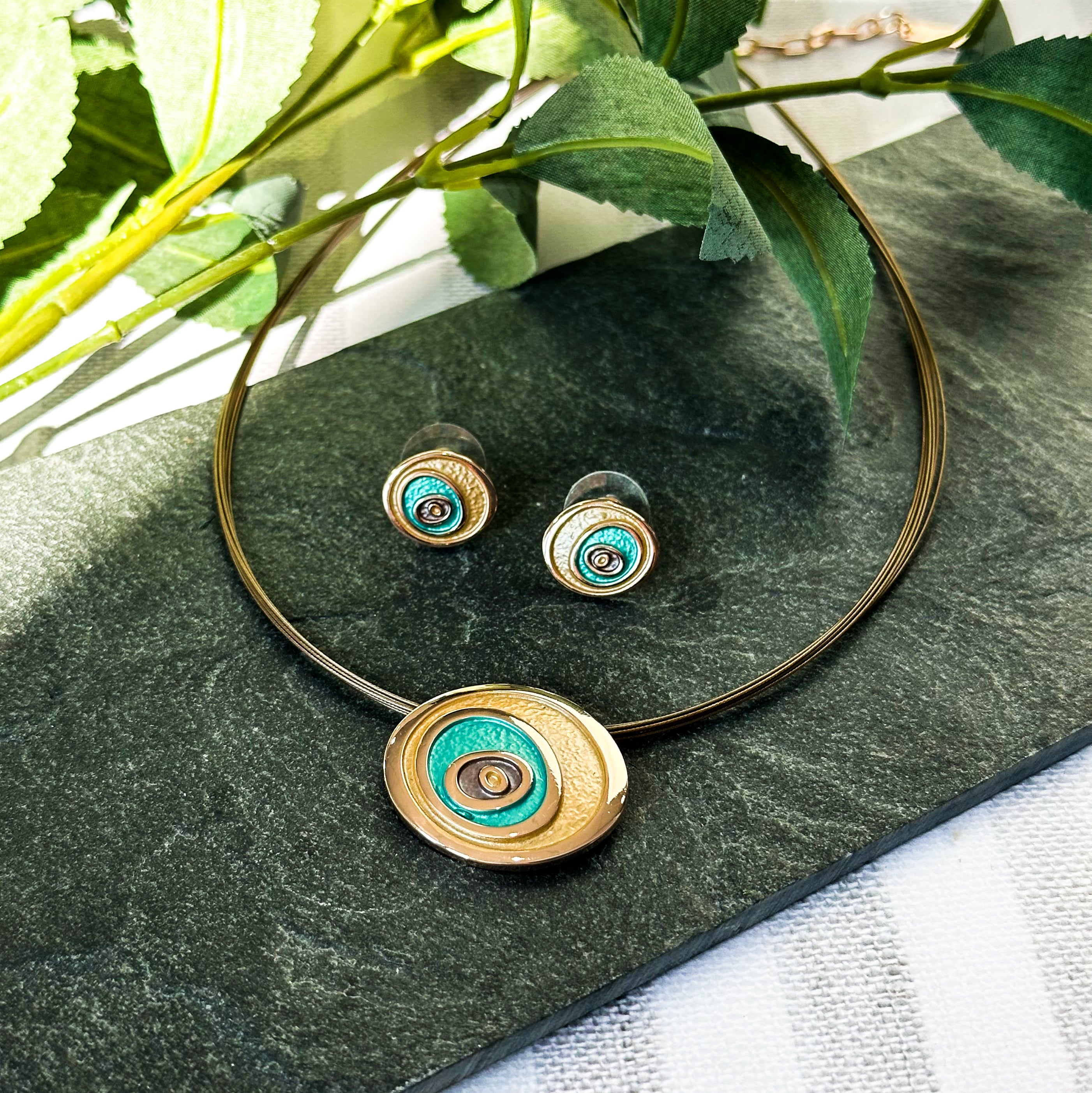 A rose gold and teal necklace on a steel wire cable chain with matching earrings against a black granite background. Teal and rose gold abstract statement necklace, abstract rose flower necklace, bohemian flower jewelry, boho natural earthy jewelry