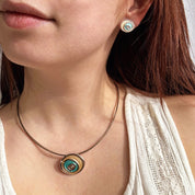 A smiling person in a white blouse wears a teal and gold abstract spiral necklace and earring set, earthy connections jewelry for her, good gifts for girlfriend or wife 2024, unique jewelry set for girlfriend anniversary, birthday, valentines day