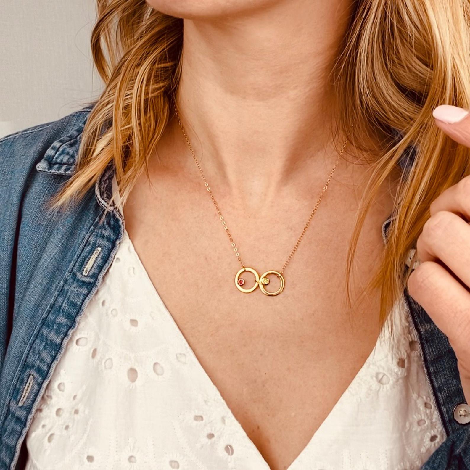 Model with white top is wearing our versatile eden necklace with two open circles and ruby and citrine gemstones. 