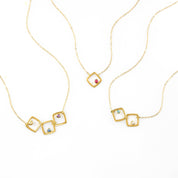 Trio of gold filled square geometric necklaces. First necklace has citrine, kyanite and purple amethyst birthstones. Center necklace features a single ruby birthstone. Final necklace has blue topaz and moonstone birthstones. 