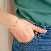 Model in green top is wearing a single gold filled dangle bracelet with ruby quartz, citrine, garnet, aqua chalcedony and peridot gemstones. gift for her, gift for mom, dangle charm bracelet