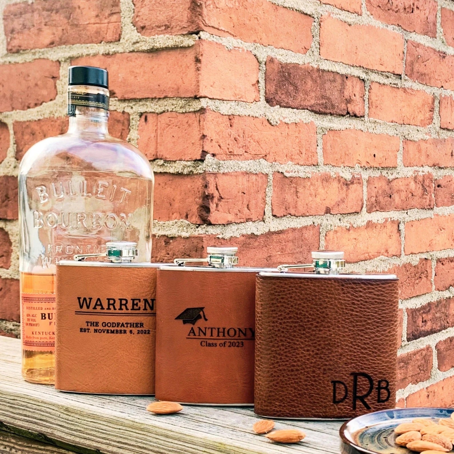 Three custom engraved leather flasks in honey with name and message, cinnamon for the college graduate and espresso with monogram.
