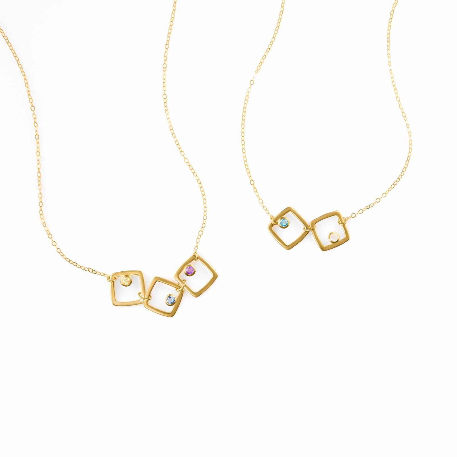Two gold filled square geometric necklaces on display. First necklace features three squares with citrine, kyanite and purple amethyst birthstones. The second necklace has 2 squares with blue topaz and moonstone birthstones. 