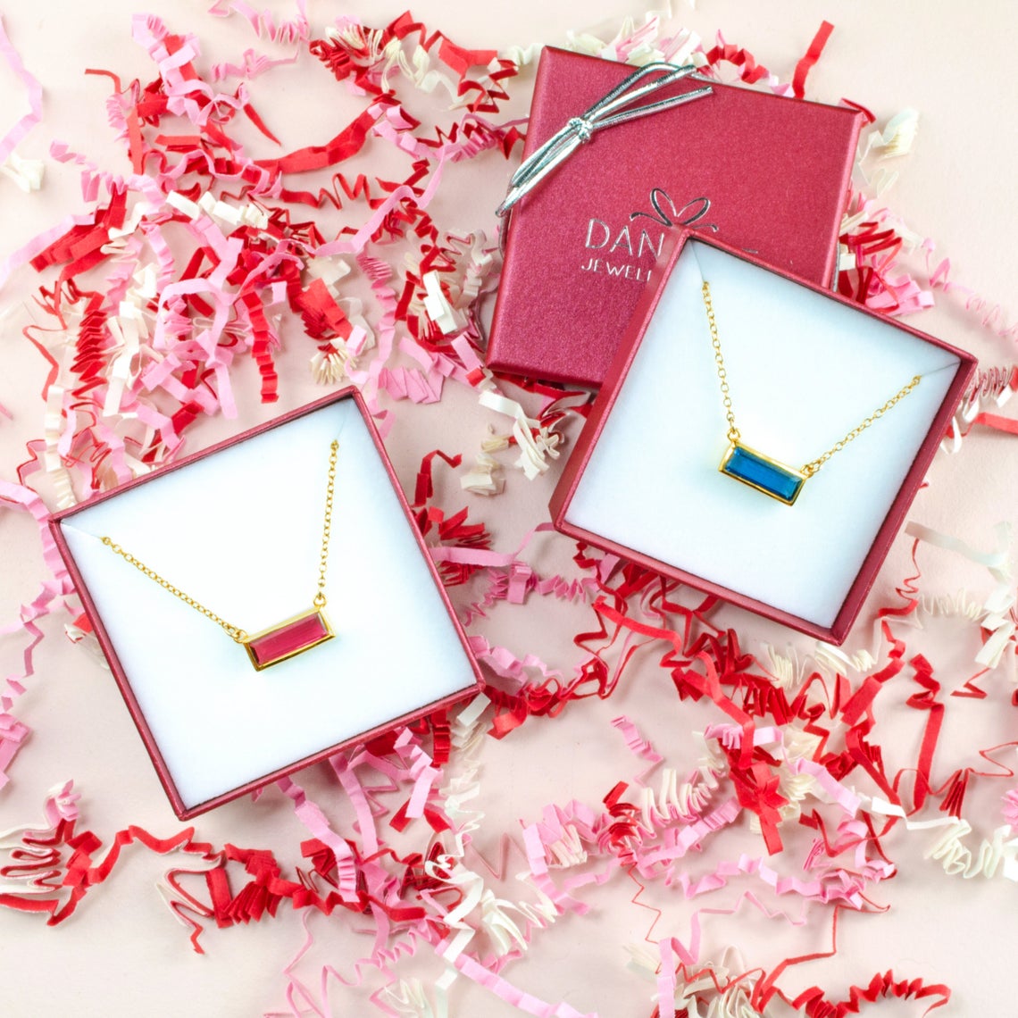 An overhead shot of a garnet and kyanite adira necklaces. Birthstone bar jewelry, modern gemstone bar jewelry. minimalist birthstone jewelry, necklace length as shown on model with white top. most popular length is 18 inches. jewelry gift, necklace gift for her, anniversary gift, christmas gift, valentine's day gift, wedding jewelry, bridesmaid's jewelry, gift for mom, gift for wife, gift for girlfriend, gift for grandma, mother's day gift