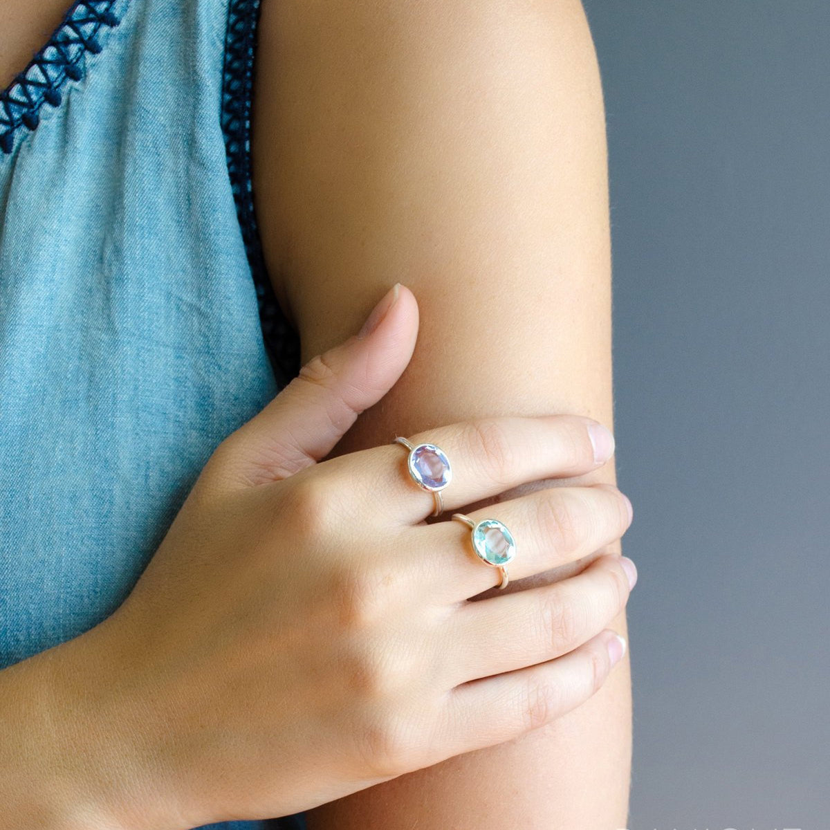 Model in blue top is sterling alexandrite birthstone and blue topaz rings. june birthstone, purple birthstone, purple gemstone, purple gem, birthstone rings stackable bezel set, stacking ring