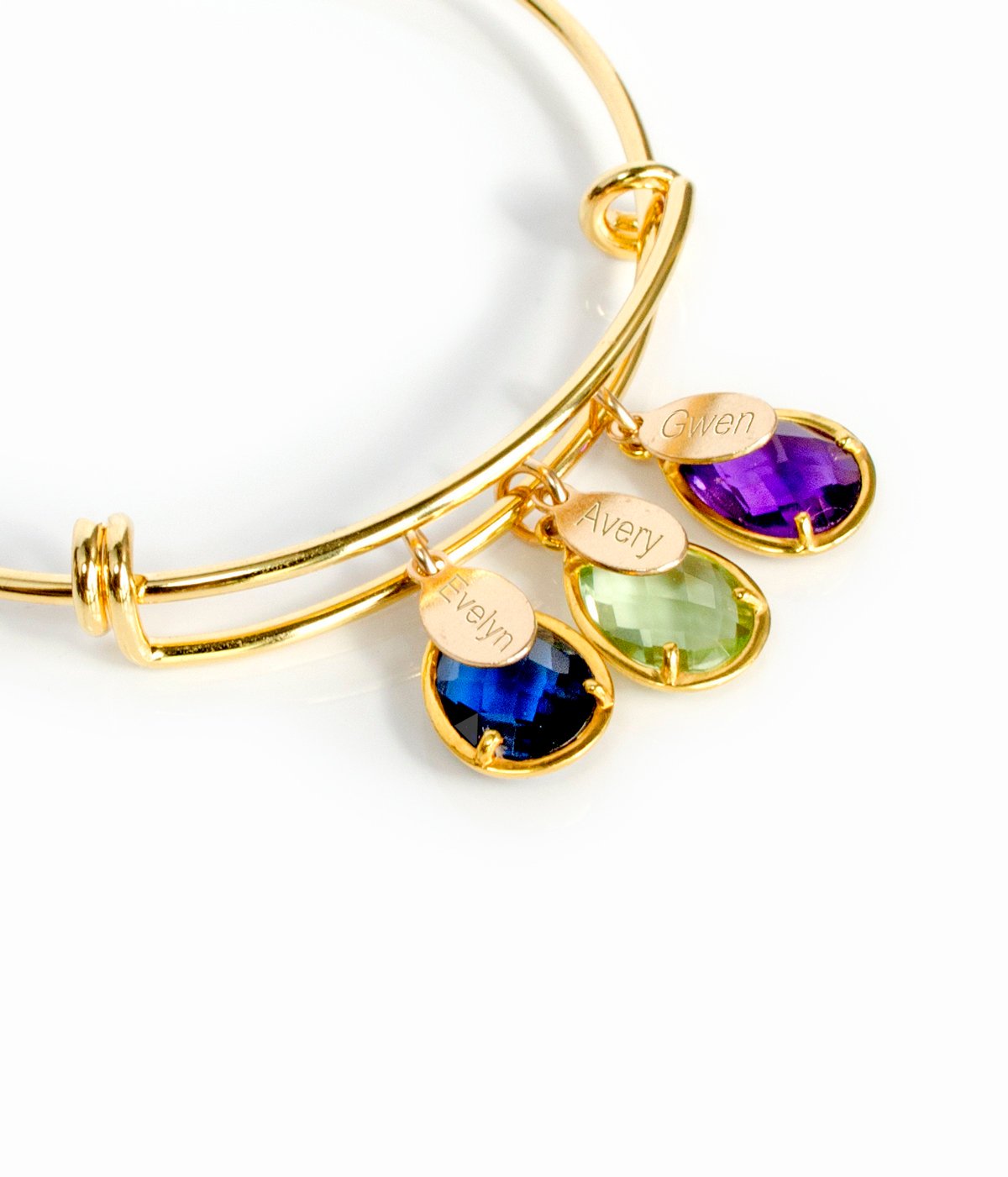 Gold bangle on top with detailed view of classic names engraved with kyanite, peridot and purple amethyst birthstones.